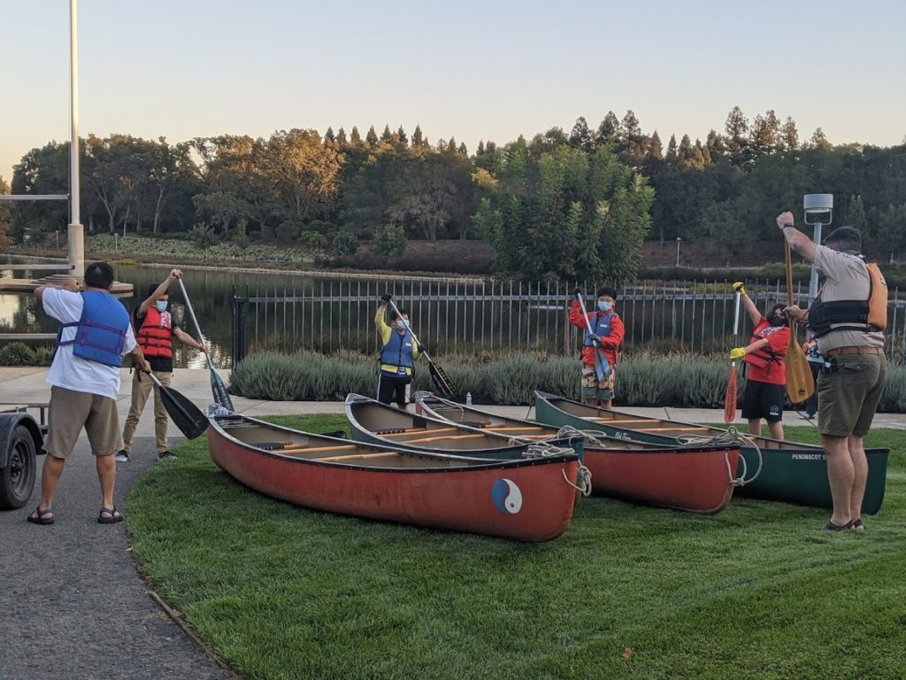 Scouts learning to paddle standing next to their canoes